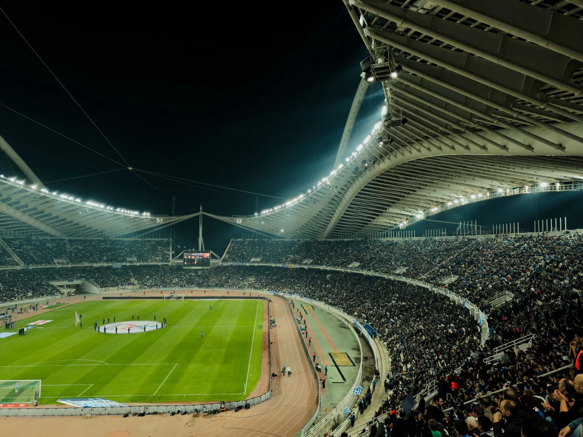 Crowded professional stadium illuminated for a major night event.